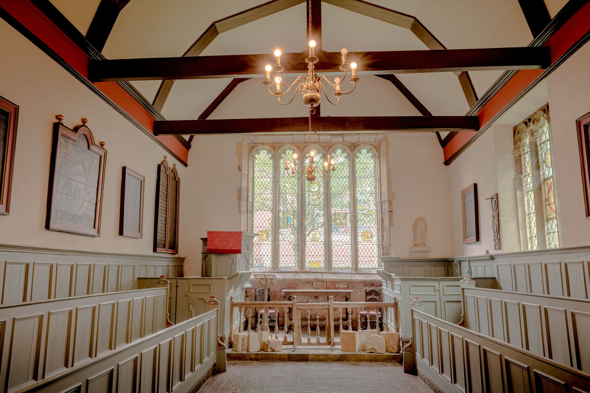Interior view of an English chapel with intricate stained glass and wooden beams.